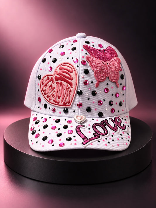 White statement cap with pink and black rhinestones, heart and love patches, and layered pink butterfly appliques